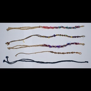 Op de afbeelding: Vijf verschillende handgemaakte vriendschapsarmbanden met verschillende kleuren en patronen. De armbanden zijn gemaakt van touw en kralen.