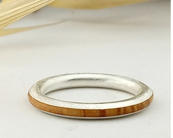 May include: A silver ring with a thin band of wood inlay.