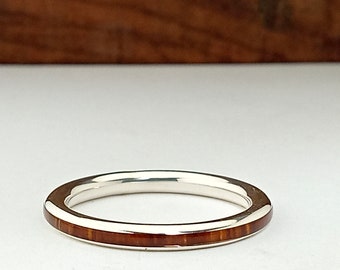 May include: A silver band ring with a thin inlay of brown wood.