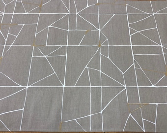 May include: A gray linen table runner with a geometric pattern of white lines and gold accents.