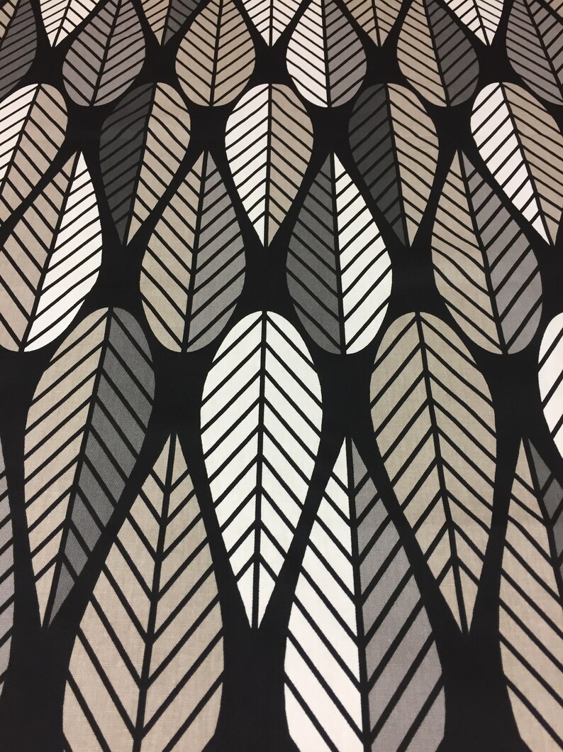 May include: Black fabric with a repeating pattern of white and gray stylized leaves. The leaves are arranged in a staggered pattern, creating a sense of movement and depth.