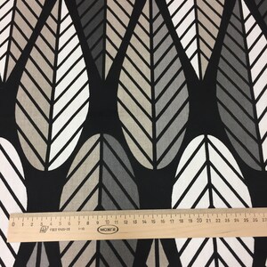 May include: Black fabric with a repeating pattern of white, gray, and beige stylized leaves. The fabric is measured with a ruler in inches.
