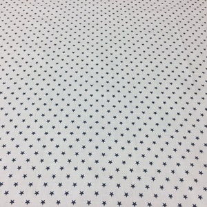 May include: White fabric with a repeating pattern of small, dark blue stars.