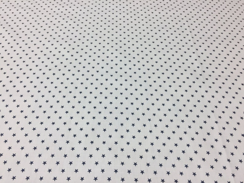 May include: White fabric with a repeating pattern of small, dark blue stars.