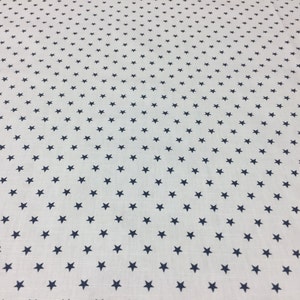 May include: White fabric with a repeating pattern of small navy blue stars.