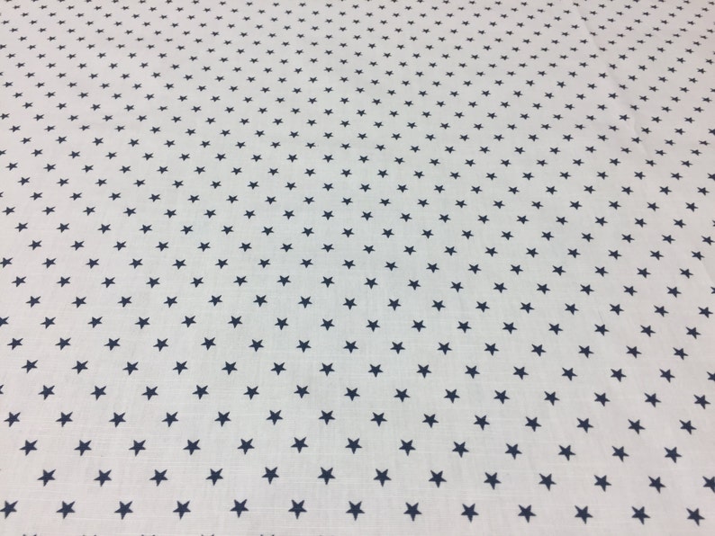 May include: White fabric with a repeating pattern of small navy blue stars.