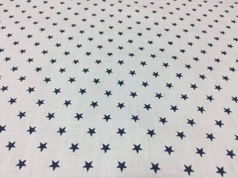 May include: White fabric with a repeating pattern of small navy blue stars.