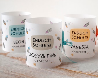 May include: Three white paper cups with colorful pencil designs and the text "ENDLICH SCHULE!"  The cups have the names Leon, Josy & Finn, and Vanessa, and the date 04.07.2021.