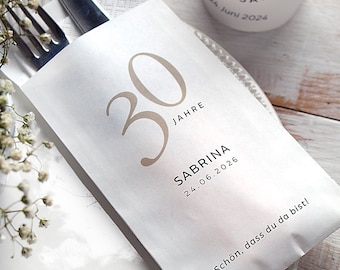 May include: White paper place card with the number 30 in a brown font, the text "JAHRE" in a smaller brown font, and the name "SABRINA" in black font. The date "24.06.2026" is also in black font. The text "Schön, dass du da bist!" is in black font at the bottom of the card.