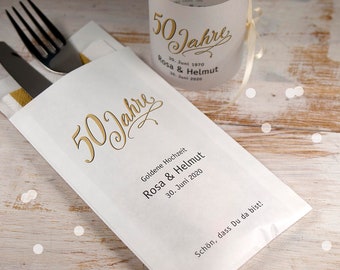 May include: White paper bag with gold lettering that says "50 Jahre" and "Goldene Hochzeit Rosa & Helmut 30. Juni 2020". The bag is folded in half and has a knife and fork inside.