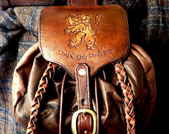 May include: A brown leather bag with a braided strap and a lion emblem. The bag has the text "Cash Uair Dhuisgear" embossed on the front.