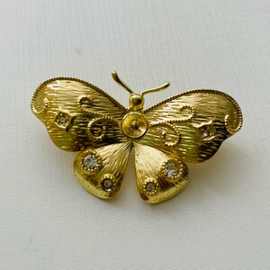 May include: A gold butterfly brooch with clear rhinestone accents.