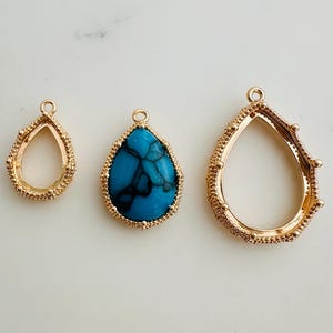 May include: Three teardrop-shaped pendants. One is empty, gold-coloured with a beaded edge. Another features a turquoise stone with black veining, set in a gold frame. The third is gold-coloured with a beaded edge.