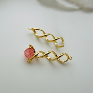 May include: Two gold-toned twisted wire earrings, one with a pink gemstone bead.
