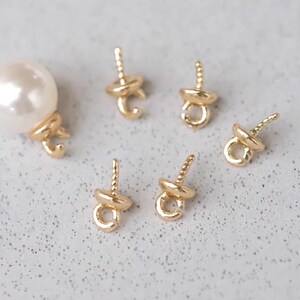 May include: Five gold-toned bead tips with a loop on the end. The bead tips have a twisted wire design. One white pearl bead with a gold-toned bead tip.