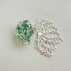May include: Silver metal leaf branch design with a green glass stone in the center.