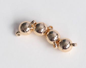 May include: Gold-toned magnetic clasp for jewelry making. The clasp is made of four round metal balls connected together.