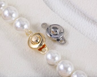 May include: A pearl necklace with a gold-coloured clasp and a silver-coloured clasp. The necklace features large, round, white pearls. The clasps are round with a small loop for attachment.