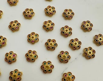 Peut inclure: Un ensemble de 20 perles en forme de fleur dorées avec des pierres précieuses colorées. Chaque perle a un trou central pour l'enfilage.
