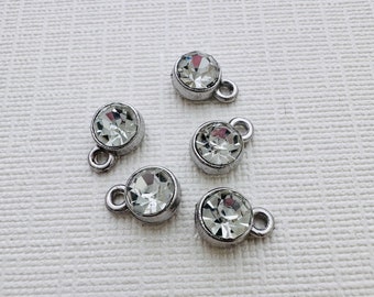 May include: Five silver-toned charms with clear crystal rhinestones. Each charm has a small loop for attaching to a bracelet or necklace.