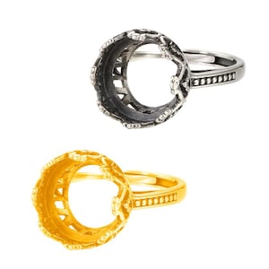 Peut inclure: Deux bagues, une argentée et une dorée, sont présentées sur fond blanc. La bague argentée présente un motif ajouré autour de la lunette et un anneau orné de petits accents décoratifs. La bague dorée a une lunette ajourée similaire et un anneau lisse.