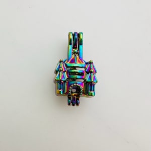 May include: A rainbow-colored castle-shaped pendant with a bail at the top for a necklace. The pendant has a detailed design with turrets, windows, and a decorative element at the bottom. The iridescent finish reflects various colors.