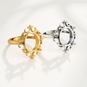 May include: Two silver rings with an oval-shaped setting. The ring on the left is gold and the ring on the right is silver.