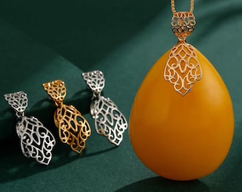 May include: A gold pendant necklace with a large, teardrop-shaped amber stone. The pendant features an ornate, openwork gold design. Three matching earrings in gold and silver are arranged to the left of the necklace.