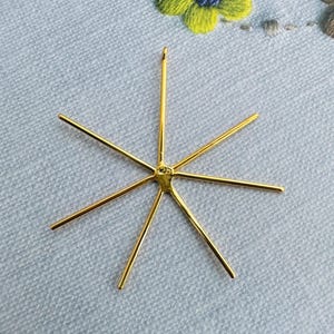 Peut inclure: Pendentif en métal doré avec un motif en étoile. Le pendentif a six pointes et une petite boucle en haut pour attacher une chaîne.