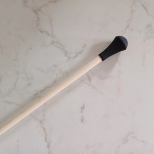 Peut inclure: Une baguette en bois avec un embout en caoutchouc noir. La baguette mesure environ 30 cm de long.