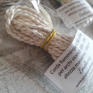 May include: A white rope made of 8 flax threads, packaged in a clear plastic bag. The label reads "Corda fiamminga 8 fili in lino per archi storici 30#-39# altezza massima 190cm Emeluna www.emelunashop.etsy.com".