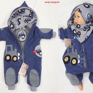 Könnte beinhalten: Blauer Baby-Overall mit Traktormotiv. Der Overall hat eine Kapuze mit Traktormusterfutter, graue Patches an Ellbogen und Füßen sowie einen Reißverschluss. Ein passender Hut und ein Lätzchen sind ebenfalls enthalten.