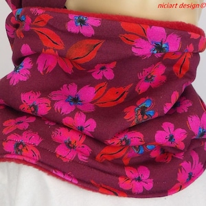 Peut inclure: Une écharpe tube bordeaux ornée d'un motif floral vif dans des tons de rose éclatant et de rouge. Le tissu présente une texture douce et le texte "niciart design ©" est imprimé dans le coin supérieur droit de l'image.