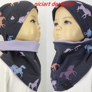 Peut inclure: Un bonnet bleu foncé et un tour de cou assorti avec un imprimé de licorne. Le bonnet a un petit patch en forme de cœur sur le côté. Le tour de cou est réversible avec un côté violet clair.