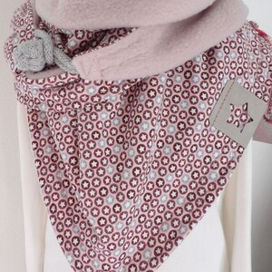 Könnte beinhalten: Rosa Fleece-Kragen-Schal mit einem weißen und rosa Sternmuster. Der Schal hat eine graue Strickbinde.