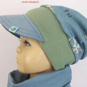 Könnte beinhalten: Blau-grüne Visor-Beanie-Mütze mit kleinem Fuchslogo. Die Mütze hat einen Schirm und ein gemustertes Design auf der Oberseite. Die Mütze ist aus weichem Material.