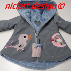 Może przedstawiać: Szara kurtka z kapturem i podszewką z niebieskiego polaru. Kurtka zapinana jest na zamek błyskawiczny i ozdobiona haftowanymi aplikacjami ptaków. Etykieta na kurtce głosi "nicicart design@"