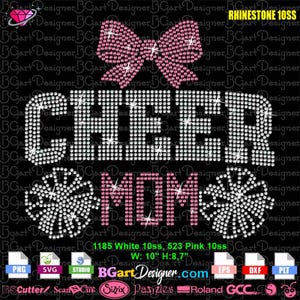 May include: A black graphic design with the words "CHEER MOM" in white and pink rhinestones. A pink bow and two white snowflake designs are also included. The design is 10 inches wide and 8.7 inches high.