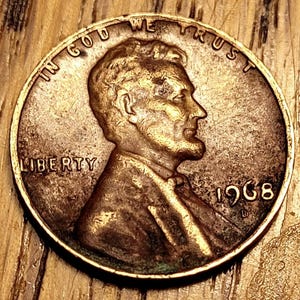 Peut inclure: Gros plan sur un penny américain de 1968. La pièce de cuivre présente le profil d'Abraham Lincoln, le mot « LIBERTY » et l'inscription « IN GOD WE TRUST ». L'année « 1968 » est visible.