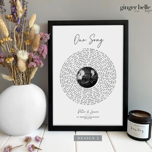 May include: A black and white photo of a couple is displayed in a circular design on a white background. The lyrics of a song are printed in a circle around the photo. The text "Our Song" is at the top of the design. The text "Peter & Laura" and "1st Wedding Anniversary 29.12.20" are at the bottom of the design.