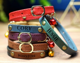 May include: A stack of five colorful cat collars with personalized names. The collars are made of leather and have gold metal buckles. The names on the collars are "Cory I'm Chipped", "Jessie", and "Winston".