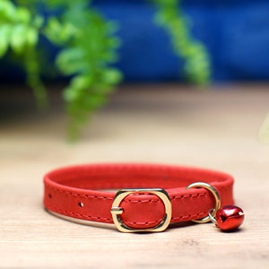 K&ouml;nnte beinhalten: Rotes Lederhalsband f&uuml;r Katzen mit goldener Schnalle und einer kleinen goldenen Glocke.