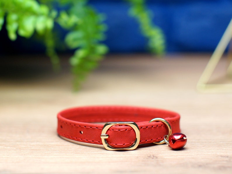 K&ouml;nnte beinhalten: Rotes Lederhalsband f&uuml;r Katzen mit goldener Schnalle und einer kleinen goldenen Glocke.