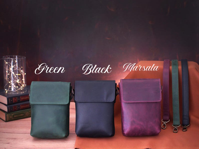 May include: Three leather crossbody bags in green, black, and marsala. Each bag has a flap closure and adjustable strap. The image also shows matching straps in coordinating colors. The word "Green", "Black", and "Marsala" are written above each bag.