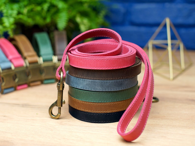 Puede incluir: Una pila de seis correas de cuero para perros en varios colores, incluyendo rosa, marr&oacute;n, azul, verde, marr&oacute;n y negro. Las correas est&aacute;n enrolladas y apiladas una encima de la otra. Las correas son todas de cuero y tienen un borde cosido.