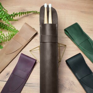 Pode incluir: Cinco estojos de couro para baquetas em diferentes cores: marrom, bege, bord&ocirc;, verde e preto. O estojo marrom tem duas baquetas dentro.