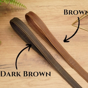 Puede incluir: Dos correas de cuero para perros, una marr&oacute;n oscuro y otra marr&oacute;n. Las correas est&aacute;n cosidas y tienen una textura lisa.
