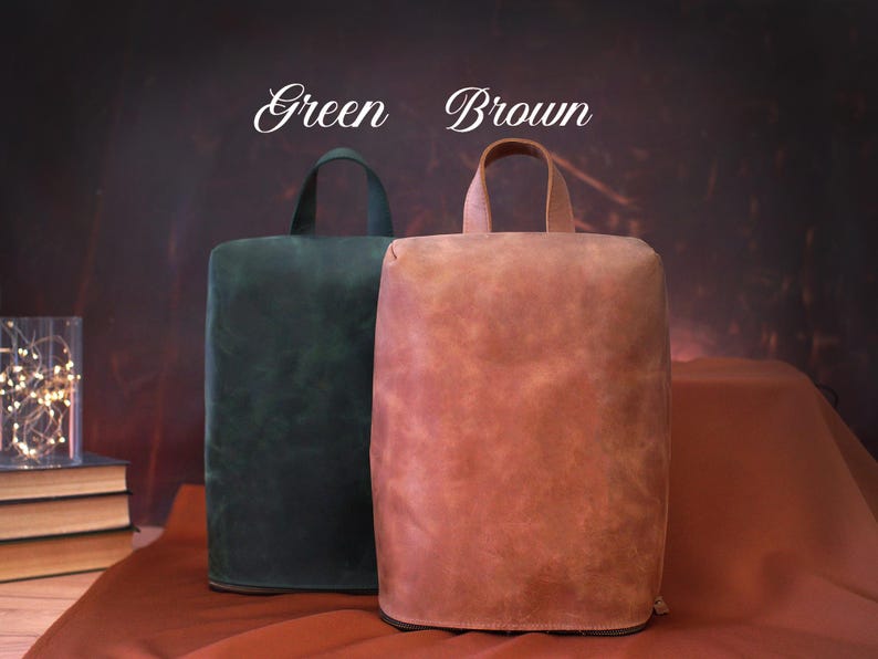 May include: Two leather bags, one green and one brown, with top handles. The bags are rectangular with rounded tops. The words "Green" and "Brown" are written above the bags in a script font.