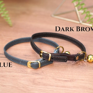 May include: Two cat collars, one blue and one dark brown, with gold buckles and bells.