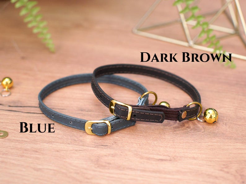 May include: Two cat collars, one blue and one dark brown, with gold buckles and bells.
